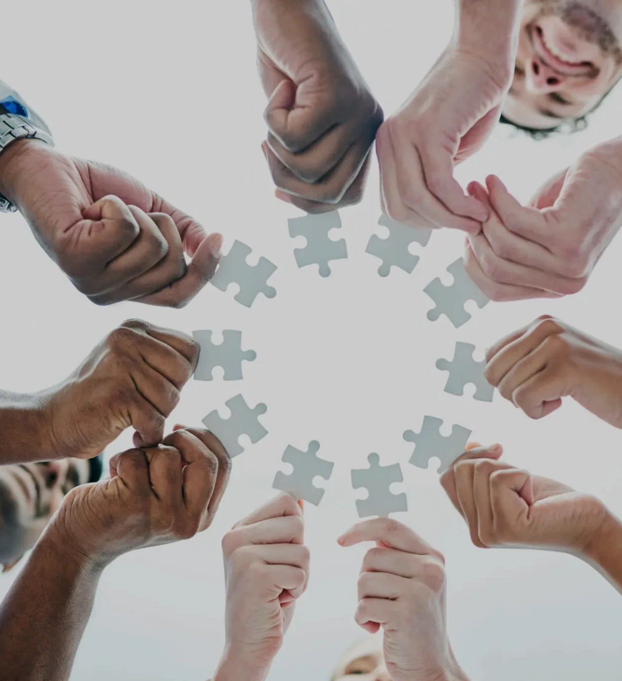 Hands holding puzzle pieces in circle