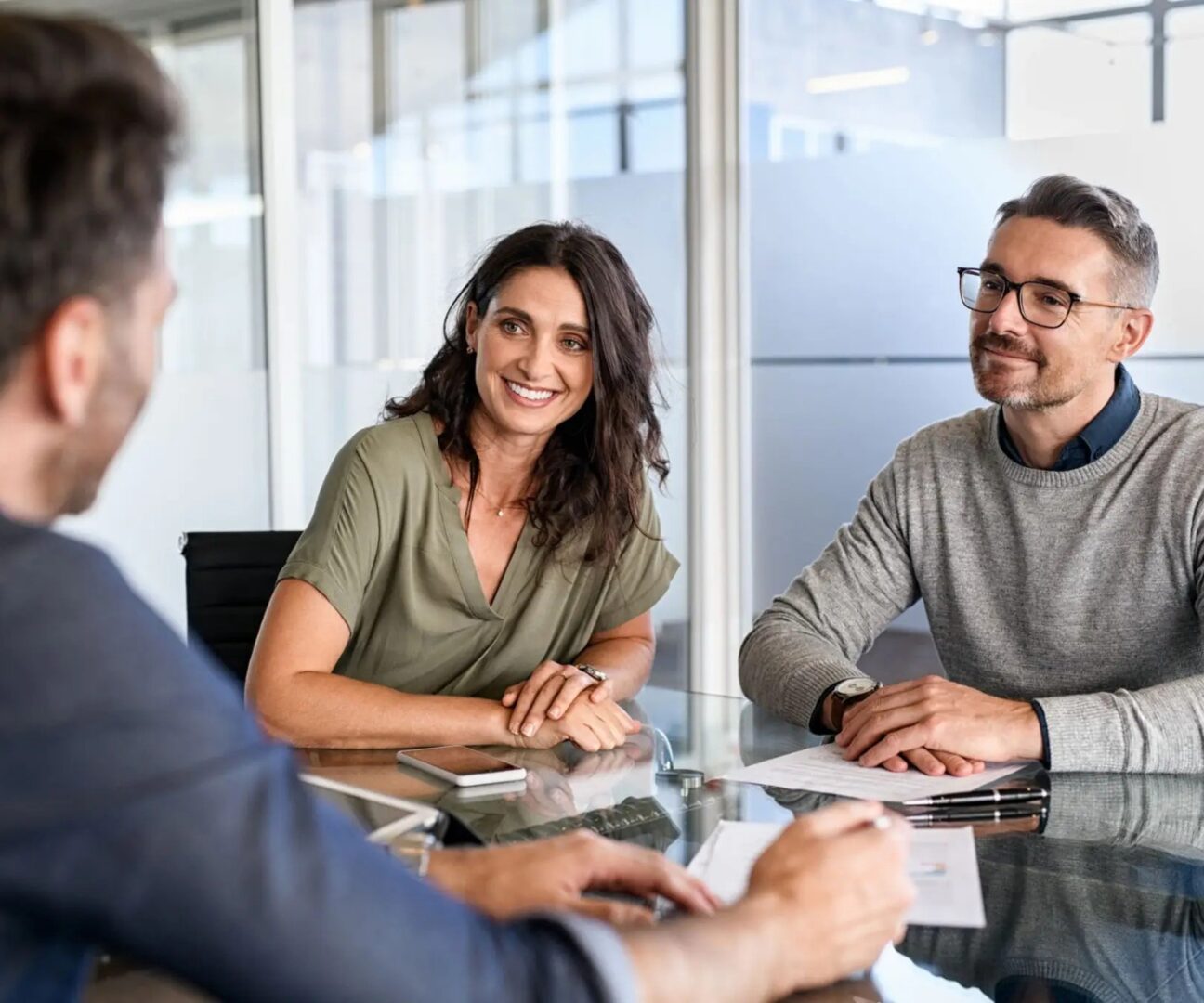 Three colleagues engaged in a friendly meeting around a table.